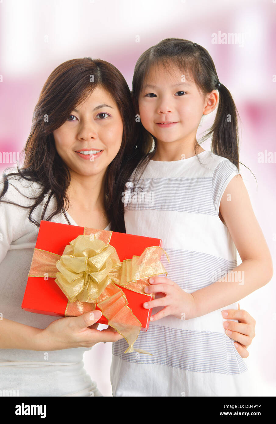 Mother's Day gift. Happy asian girl greeting young surprised mom, giving  her handmade card and wrapped gift box Stock Photo - Alamy