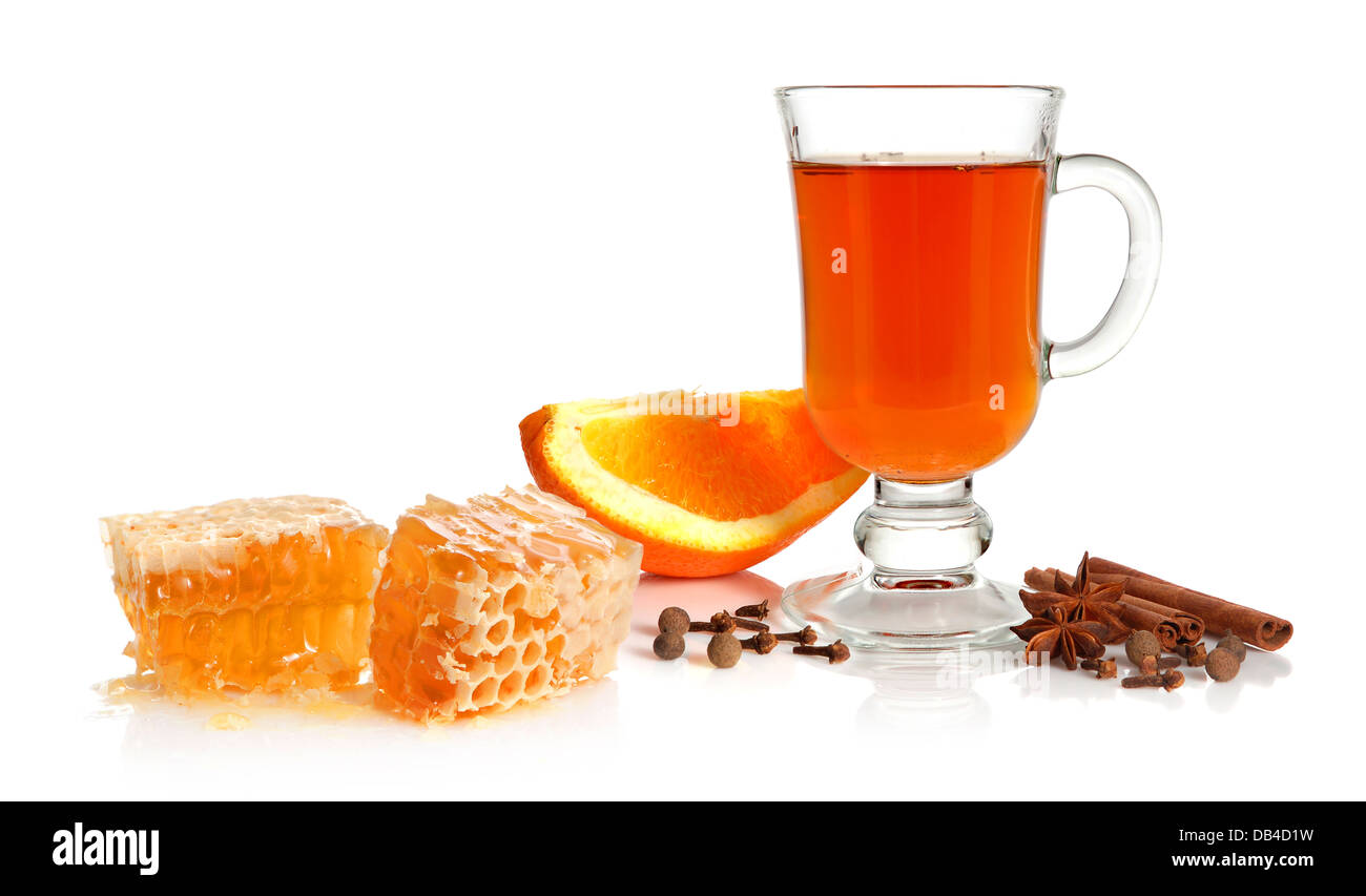 Hot tea in glass cup with spice, orange and honey on white background