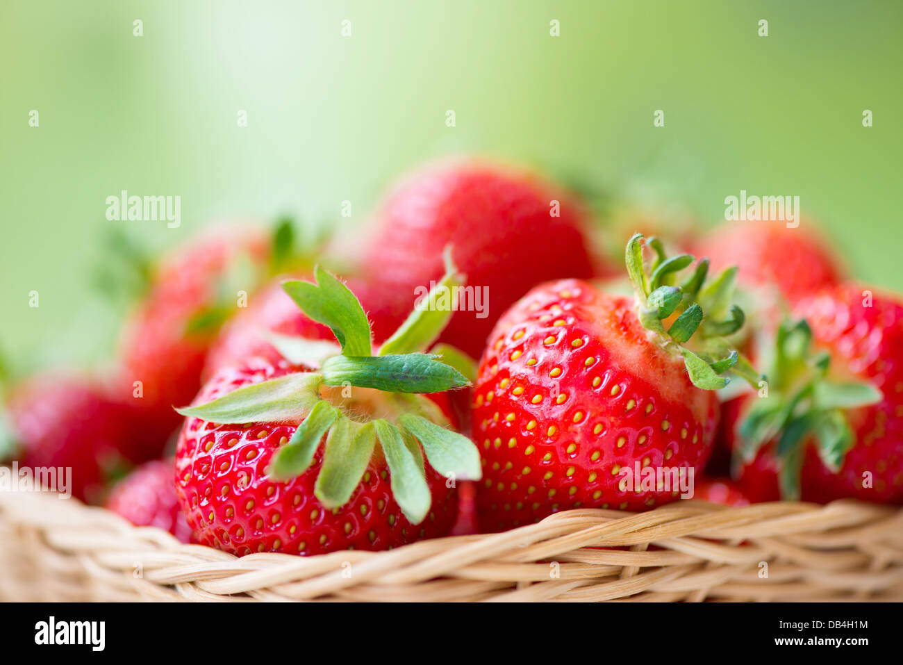Juicy ripe strawberries in basket against green background Stock Photo ...