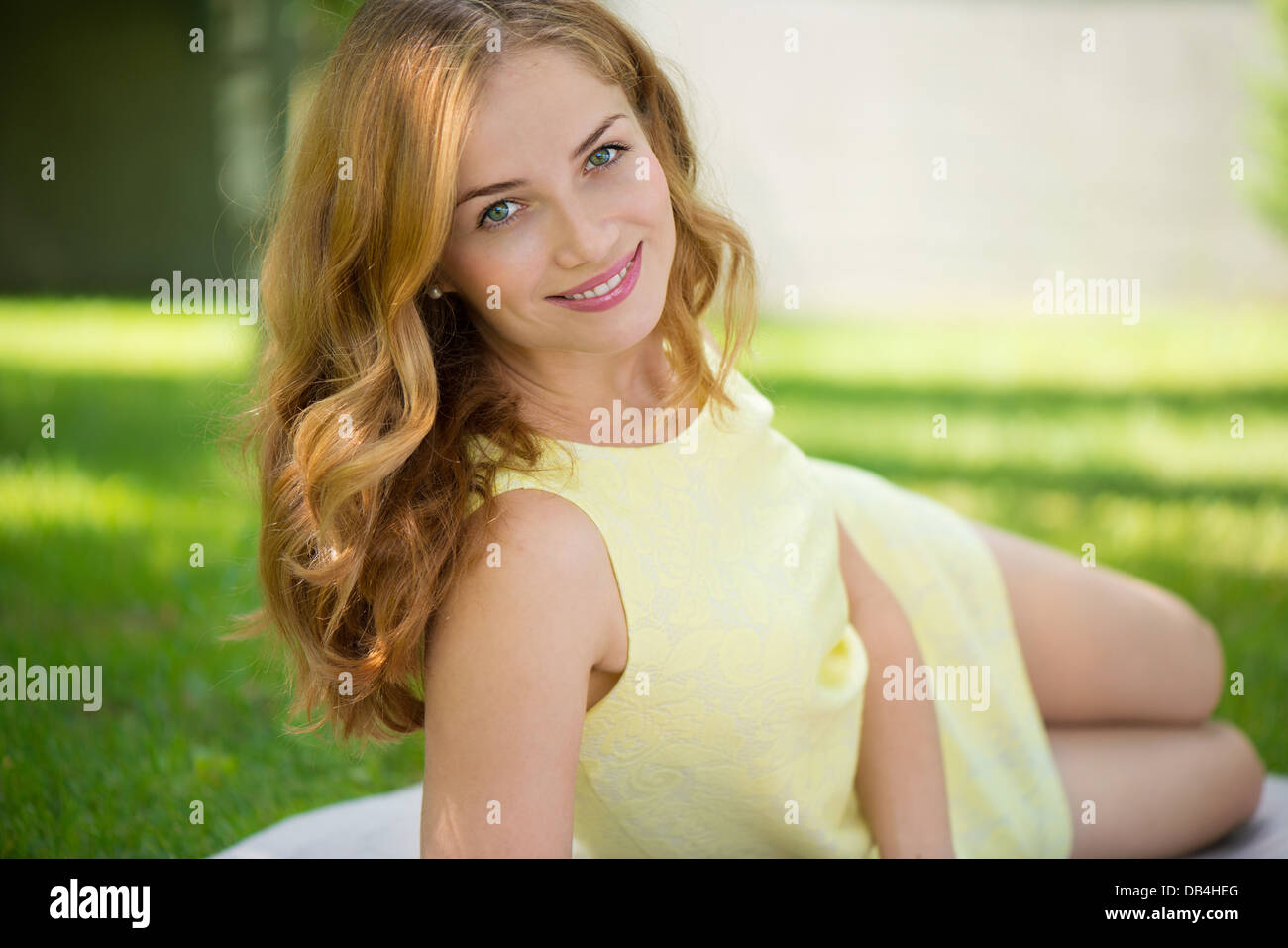 Beautiful young woman lying in park on green grass Stock Photo - Alamy
