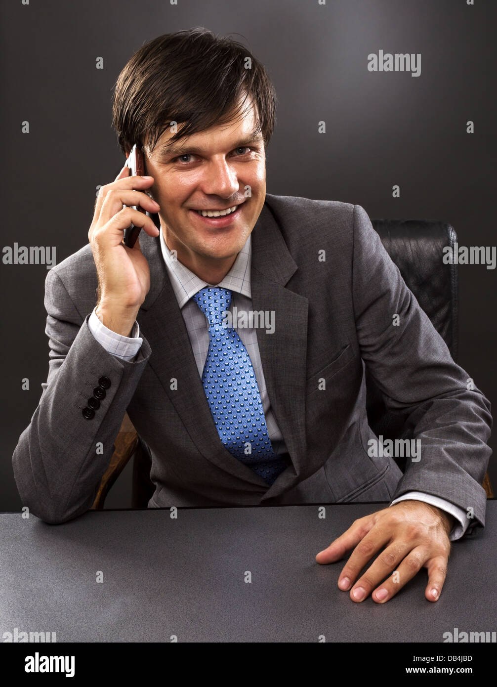 Businessman sitting at desk in office, talking on phone, smiling Stock ...