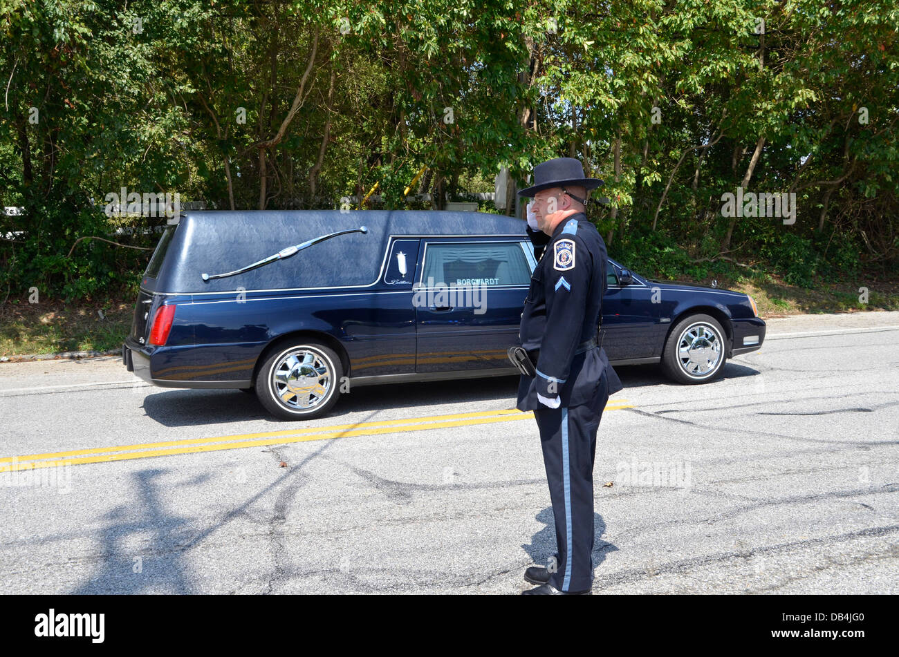 Police officer salutes a hearse carrying a policeman killed in the line of duty Stock Photo