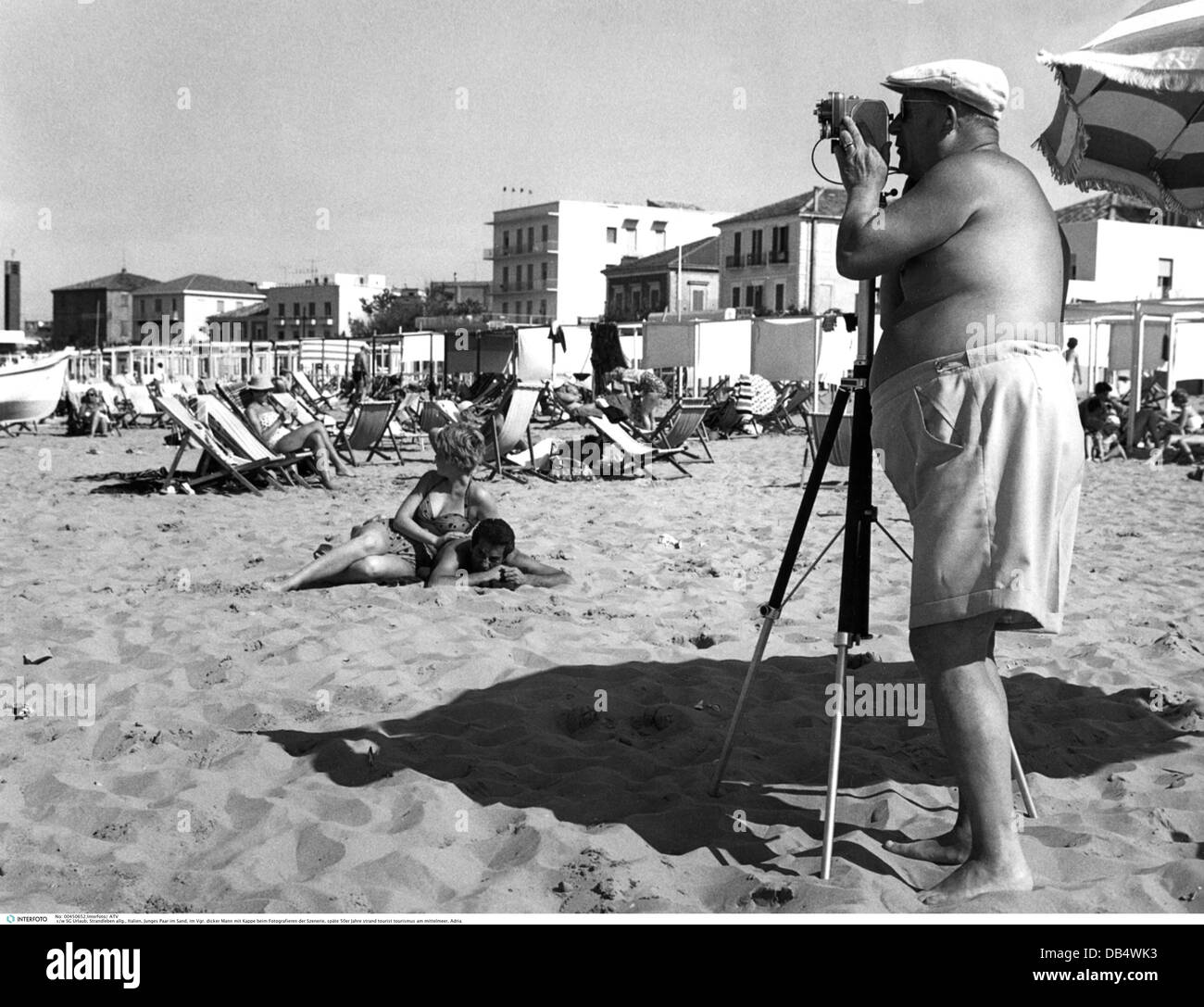 tourism, beach life, thick man with cap taking a picture of a couple lying in the sand, late 1950s, , Additional-Rights-Clearences-Not Available Stock Photo