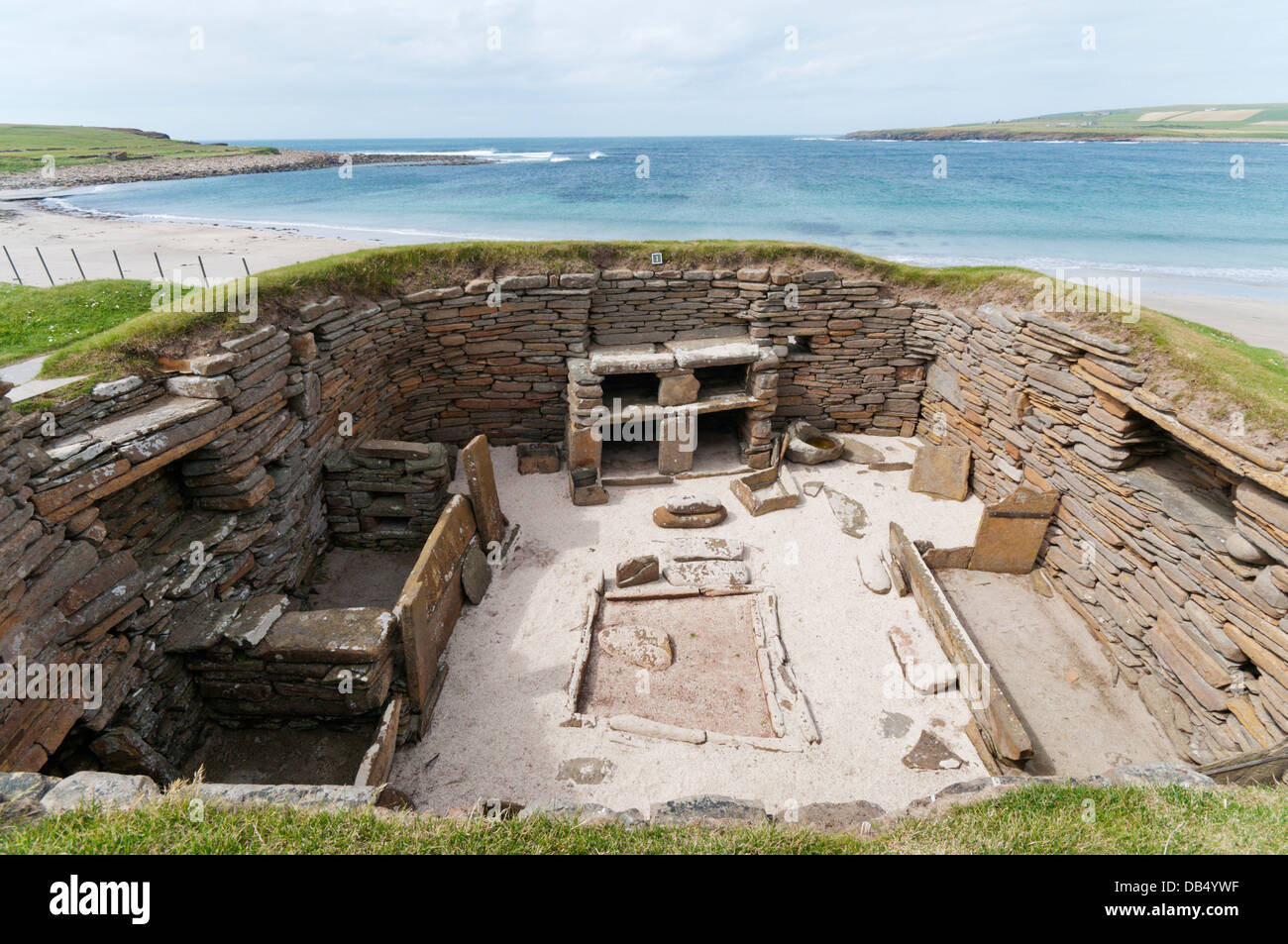 House 1 at Skara Brae Neolithic Village on Mainland Orkney with the Bay of Skaill in the background. Stock Photo