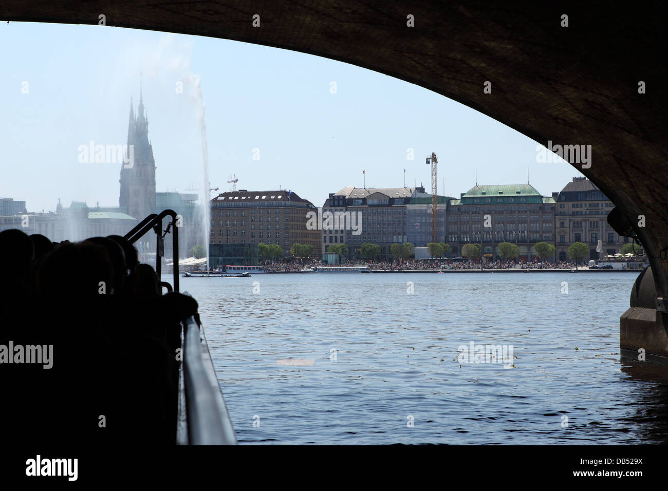 A boat cruises under a bribge and onto the Inner Alster lake (Innenalster) in Hamburg, Germany. Stock Photo