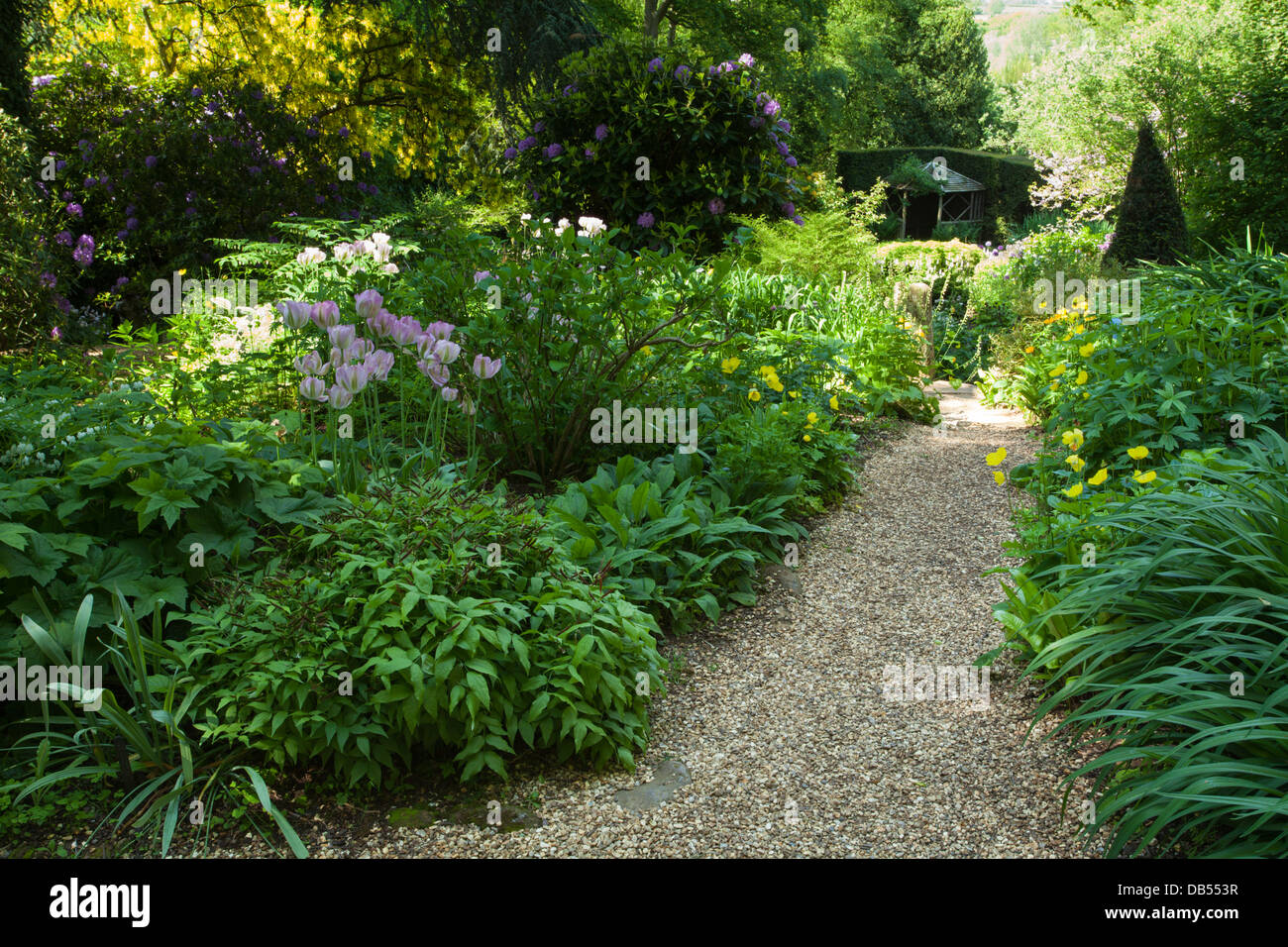 A path leads down to the summer house from the upper terrace of the Water Garden within Coton Manor gardens in early June, Northamptonshire, England Stock Photo