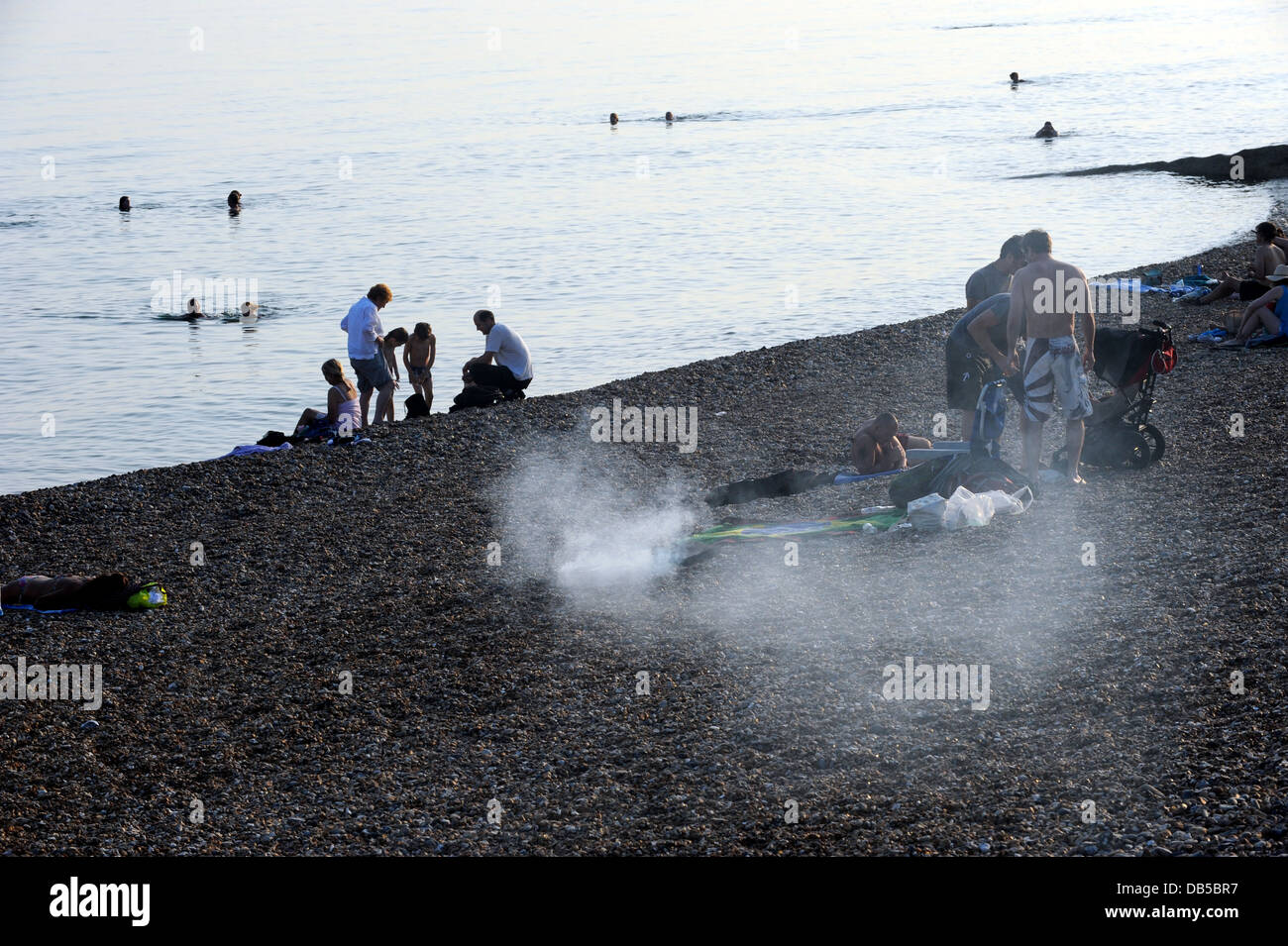 Smoke from small portable barbecues fills the early evening air on Brighton beach Stock Photo