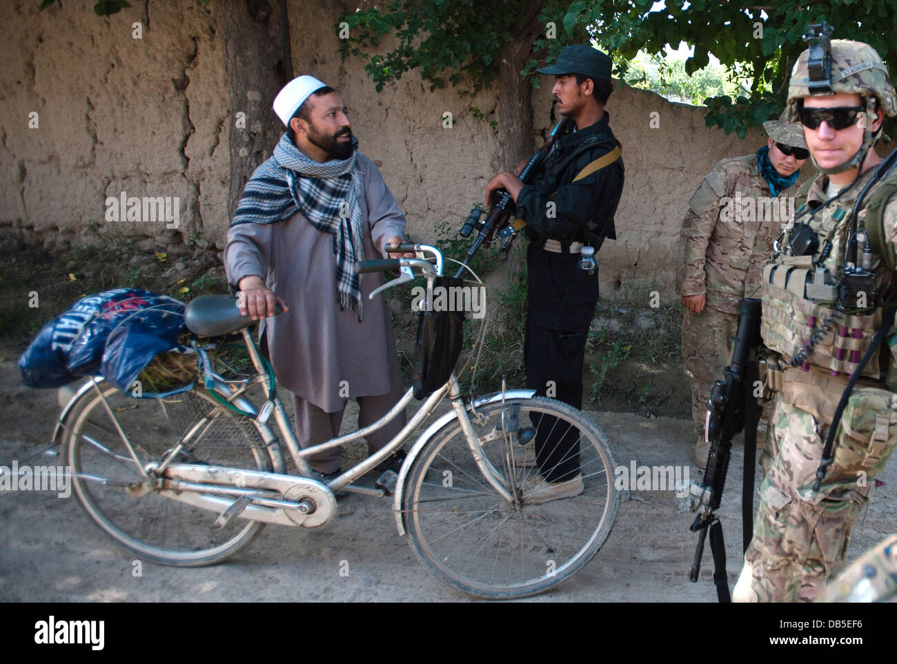 A US army soldier and Afghan Local Police question a villager during a joint patrol near Forward Operating Base Salerno July 4, 2013 in Khost province, Afghanistan. Stock Photo