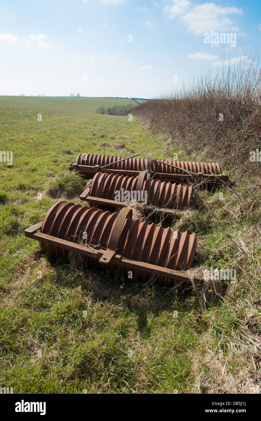 Farm rollers in field alongside hedge Stock Photo