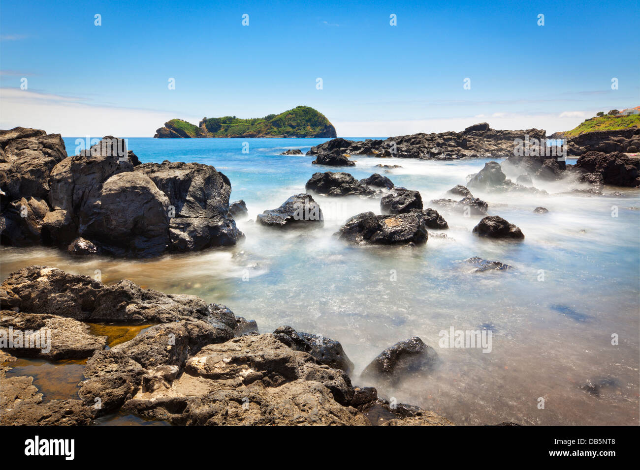 View from the rocky coast of São Miguel to the islet of Vila Franca. Long exposure shot. Stock Photo
