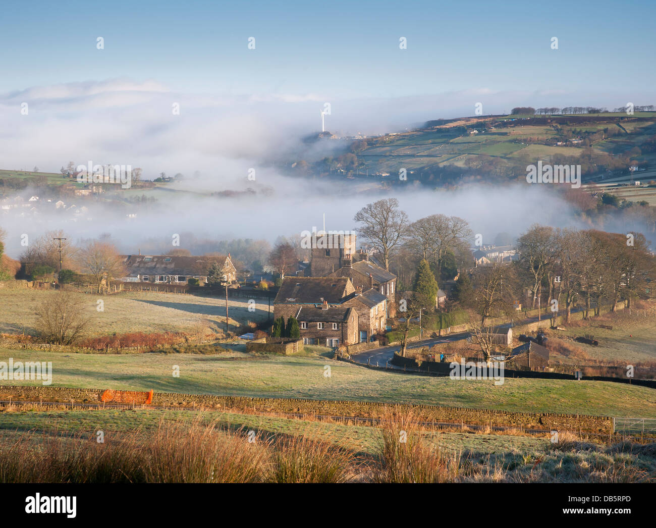 thinning mist cover revealing the church of st mary in oxenhope in the yorkshire dales Stock Photo