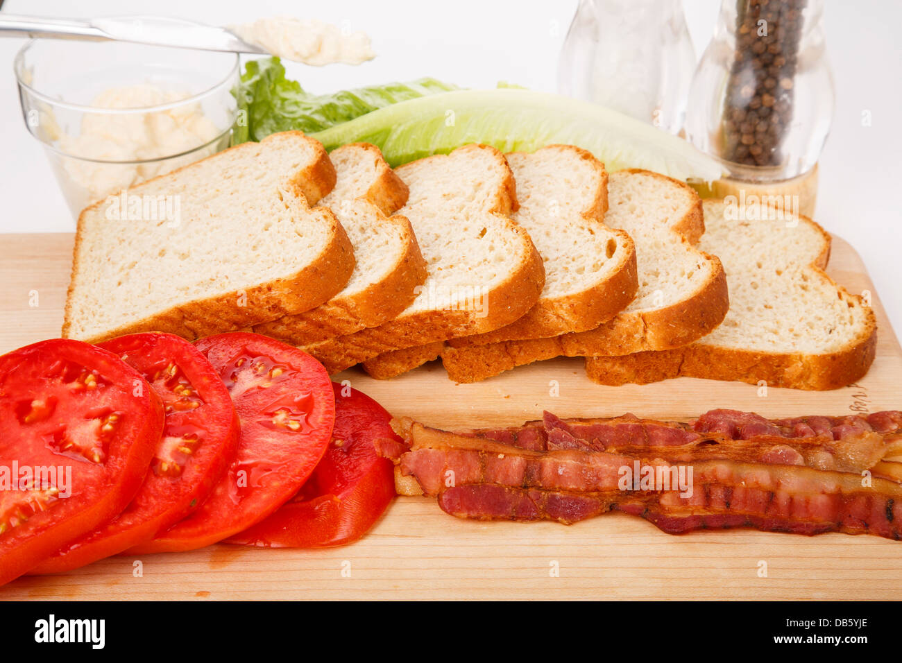 Sliced bread and tomatoes, cooked bacon, lettuce, mayonnaise and spices for a BLT sandwich Stock Photo