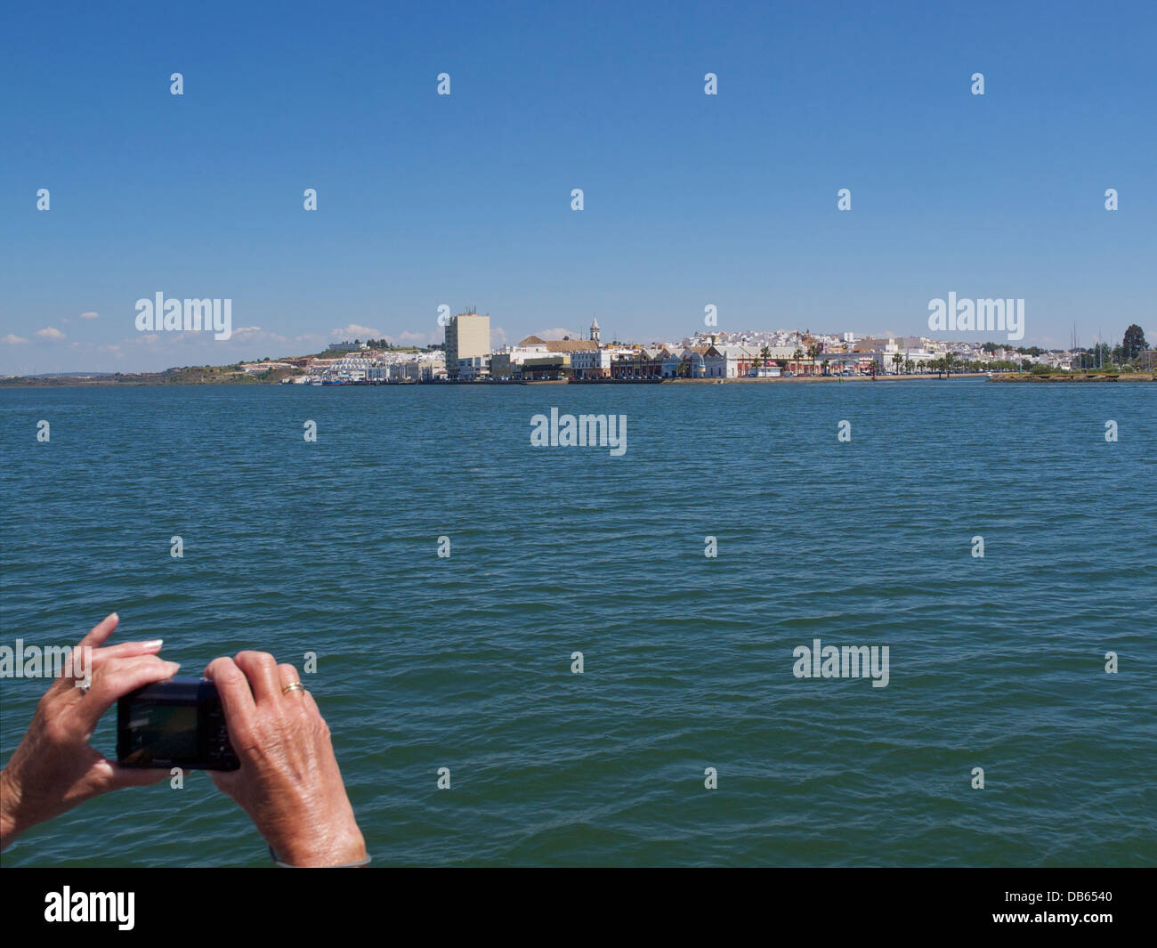 holiday snap, woman taking digital picture of Ayamonte, Spain, from the ferry on the Rio Guadiana Stock Photo
