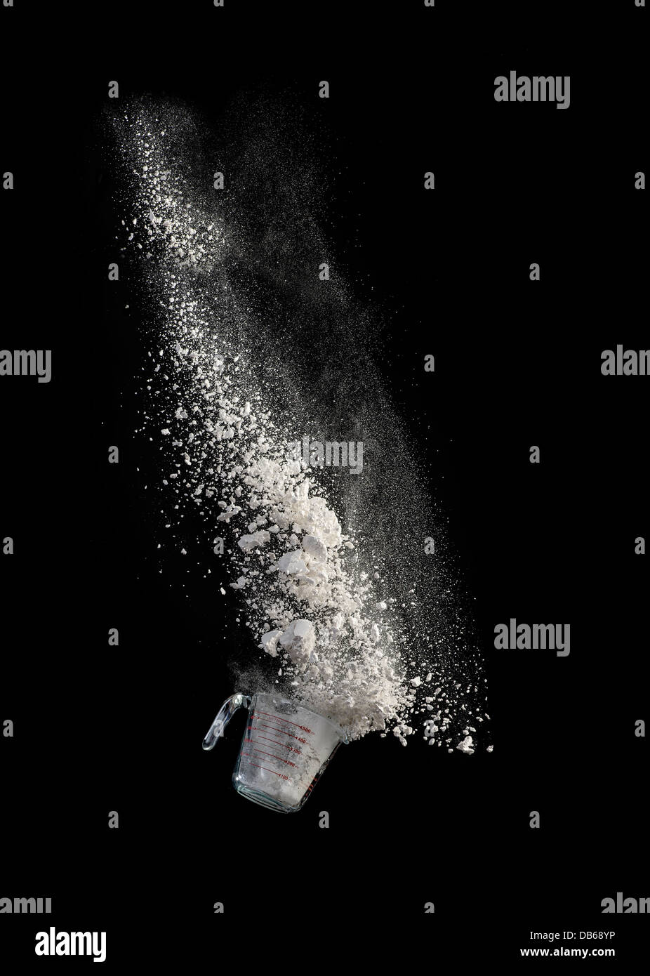Measuring Cup Falling With Flour Spilling Out Stock Photo