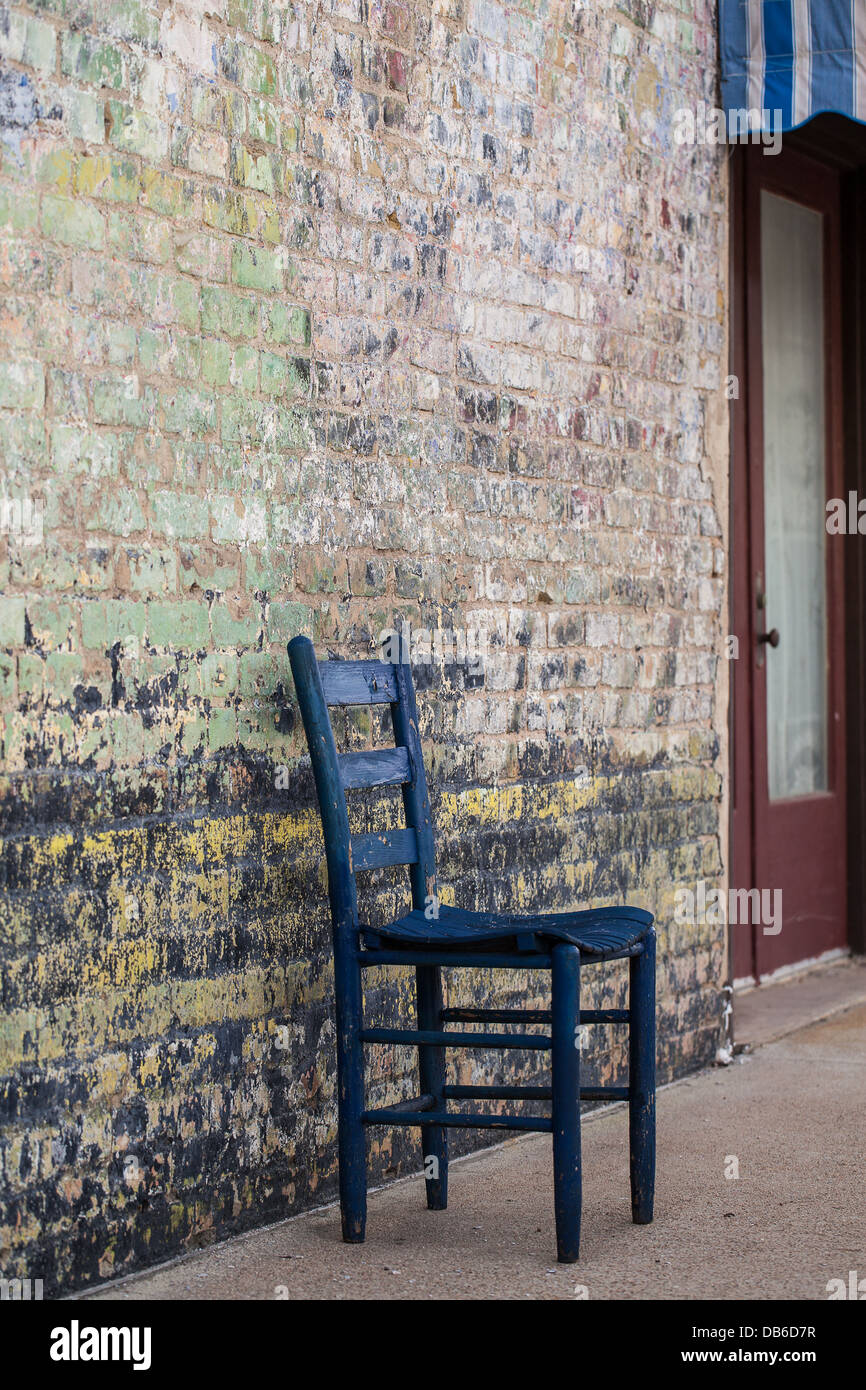 Black Chair against Faded Painted Brick Stock Photo