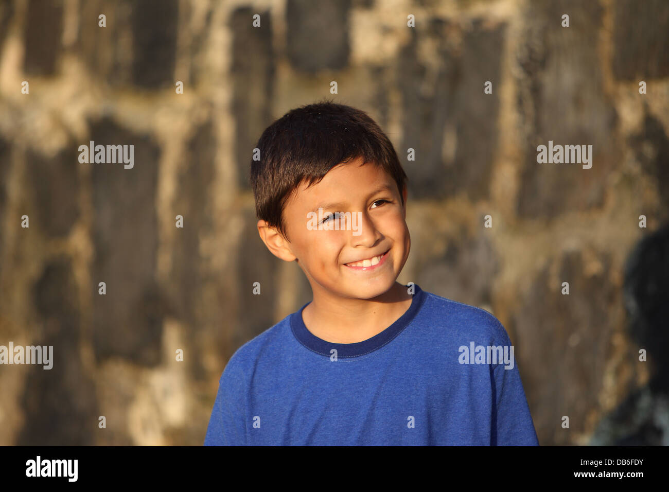 Portrait of a young smiling boy near sunset by an old wall Stock Photo