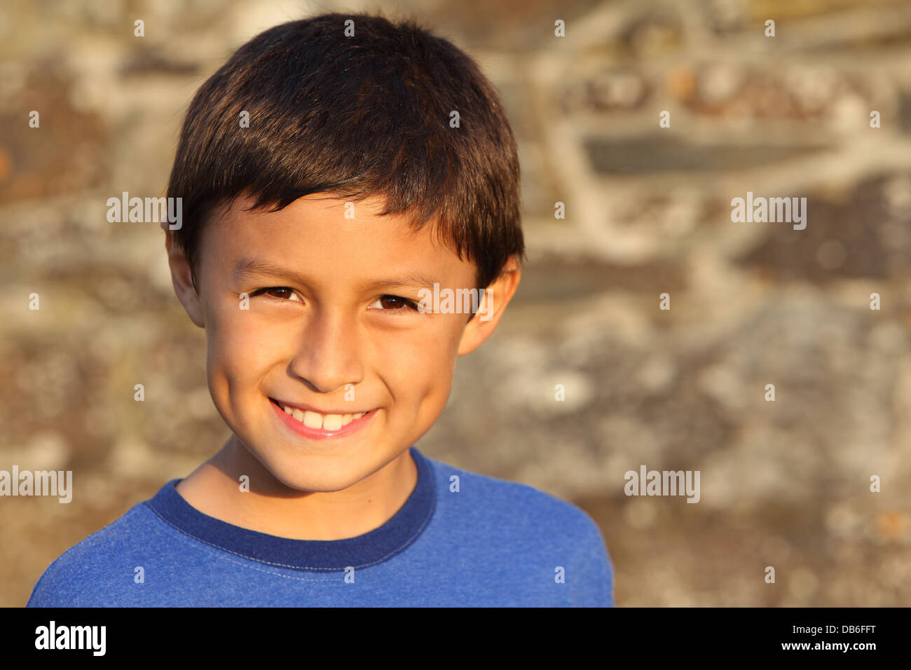 Portrait of a young smiling boy near sunset by an old wall Stock Photo