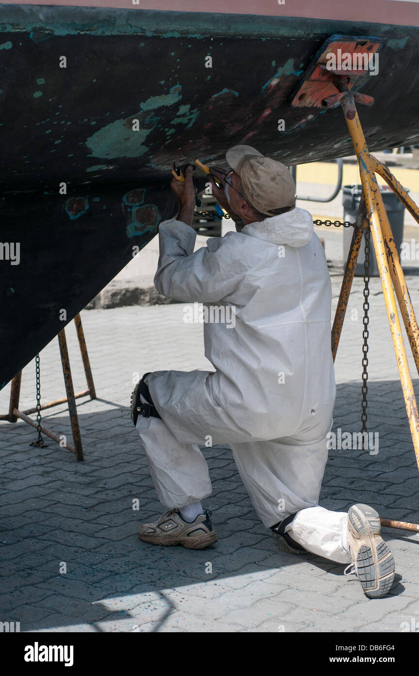 Man performing maintenance on the hull of a boat, Granville Island