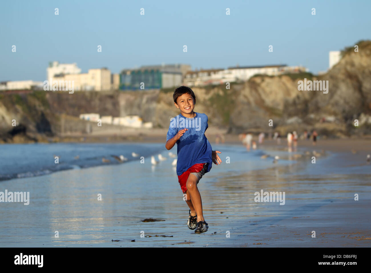 Young boy plays and runs in the surf along an English beach near sunset Stock Photo