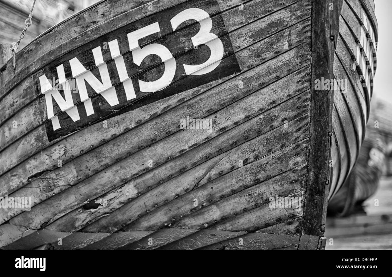 Old wooden drydocked boat with identification numbers in black and