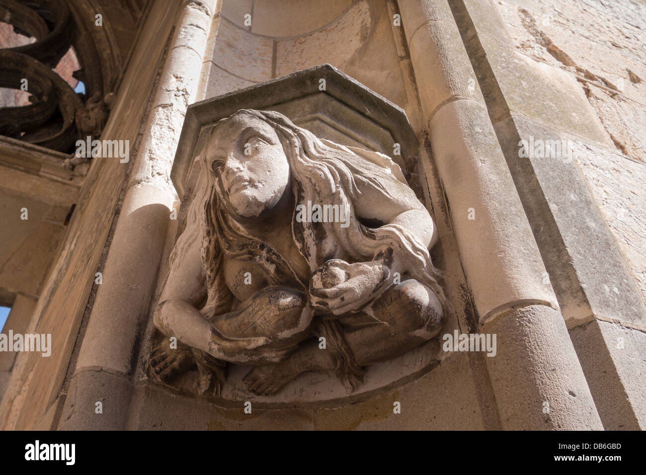 Woman Sculpture with Graffiti. Old graffiti from the early 20th century adorns this enigmatic sculpture on the gothic portico Stock Photo