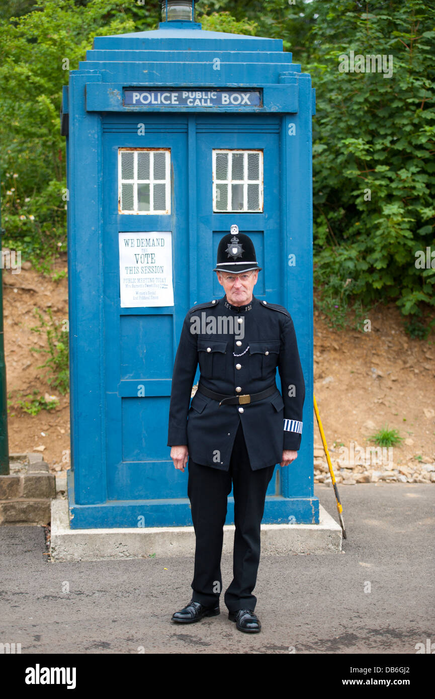 edwardian uniformed policeman standing before a blue police box Stock Photo