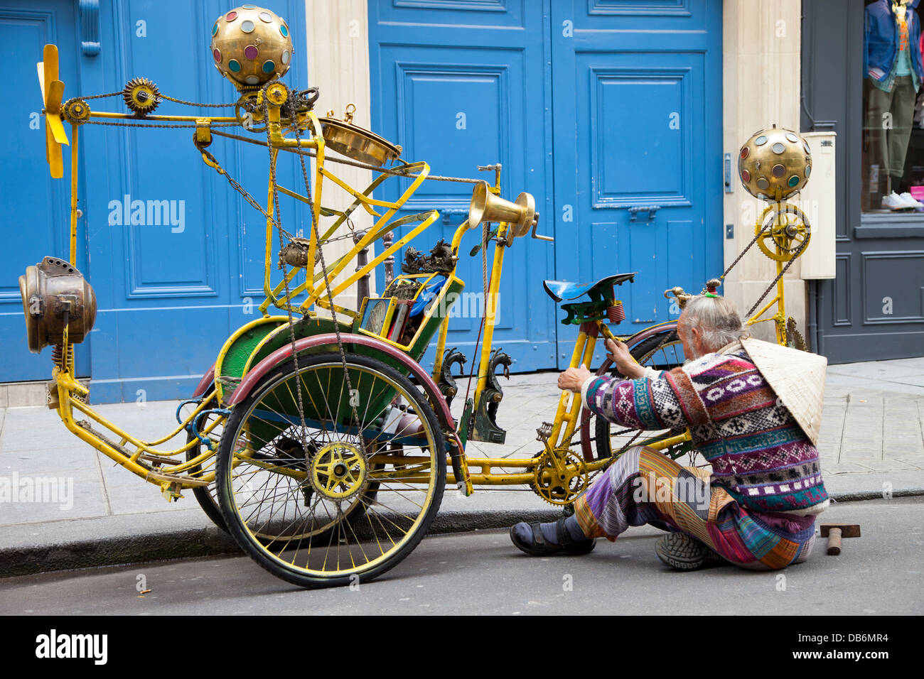 Man fixing homemade music-playing bicycle taxi along the street in les Marais, Paris France Stock Photo