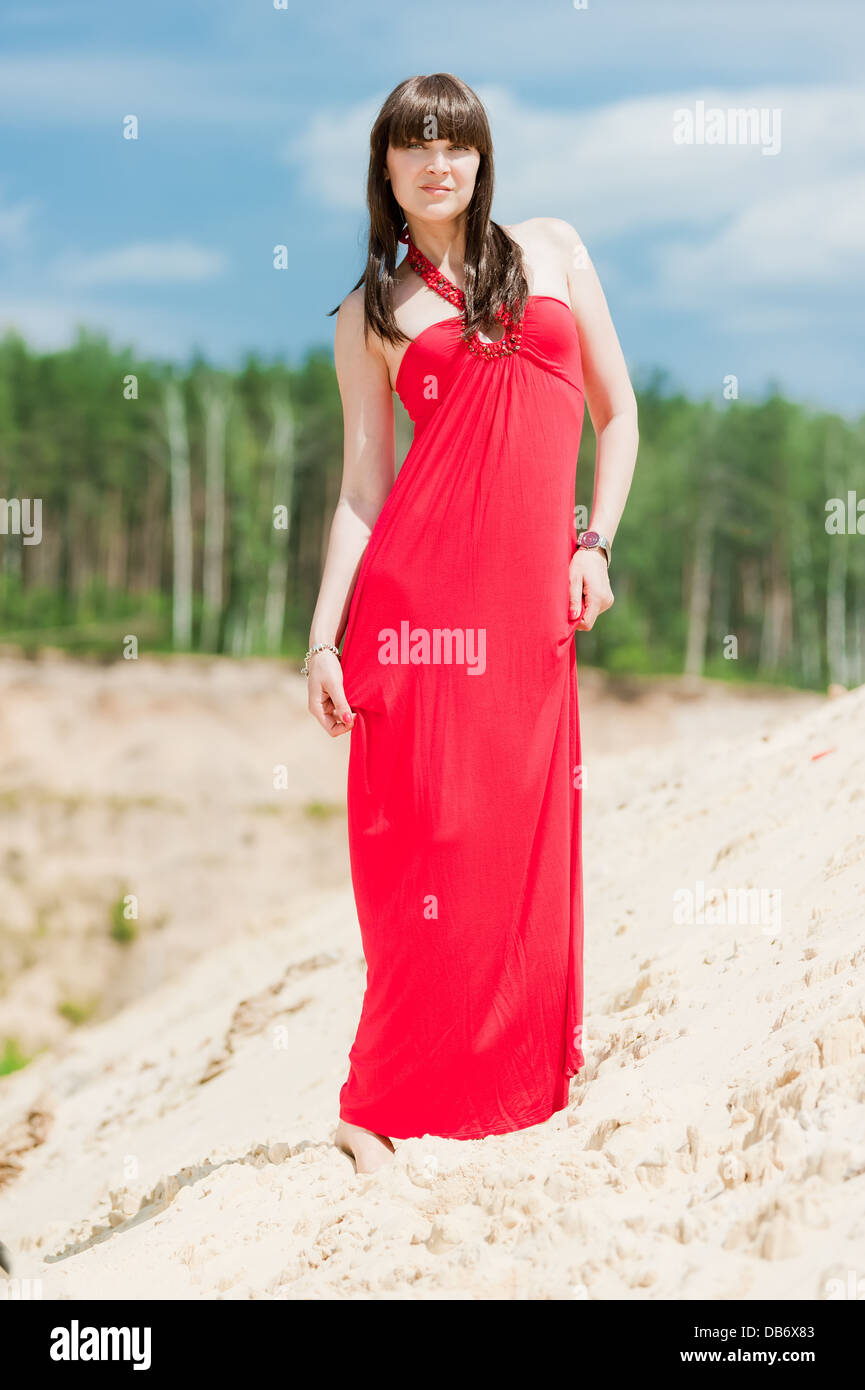 A girl in a red dress posing on a sand dune Stock Photo - Alamy