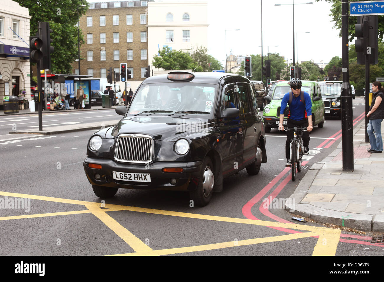 London street scene with a black taxi cab and cyclist. 4th July 2013 Stock Photo