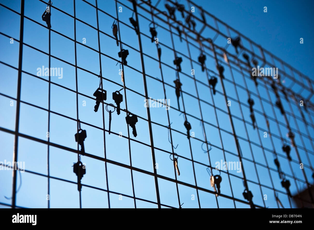 Keys hooked to a metal grid type fence at dusk Stock Photo