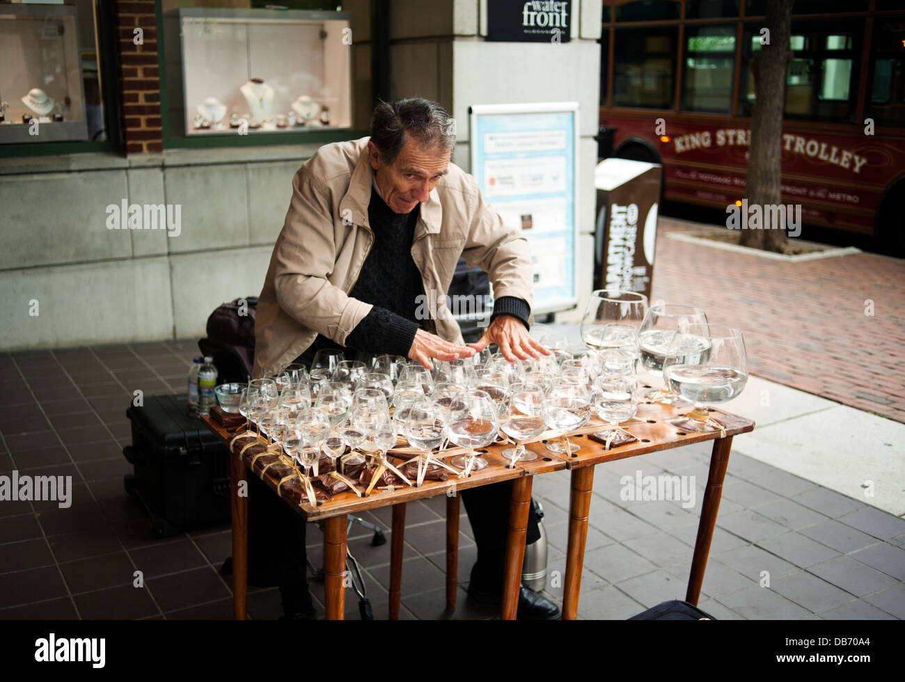 A man playing musical glasses known as a glass harp in Old Town Alexandria, Virginia Stock Photo