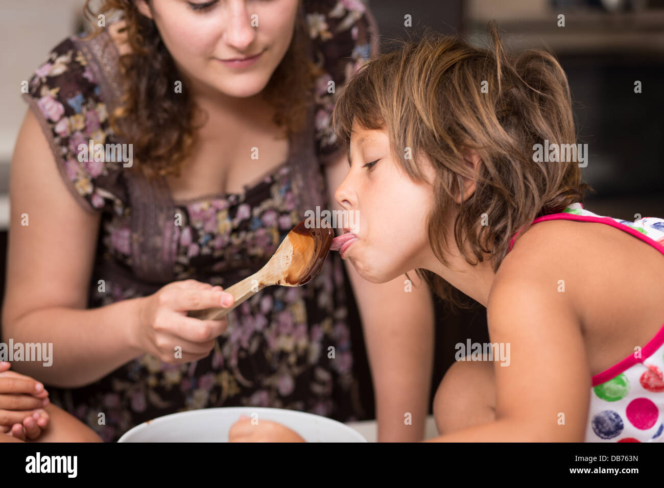 Young girl licking chocolate off a spoon Stock Photo
