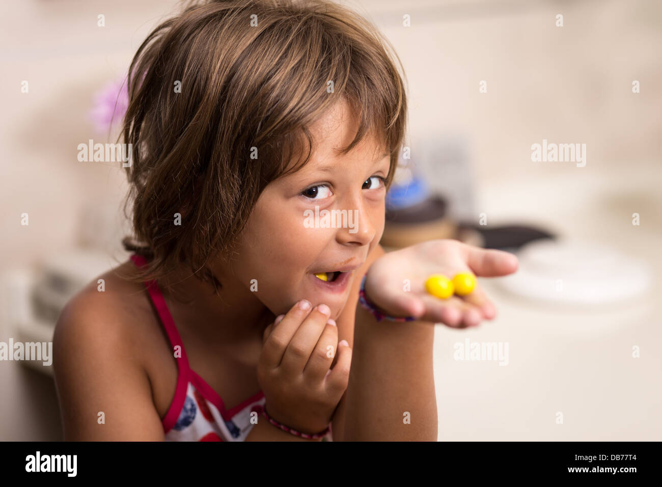 Young girl eating yellow chocolate candy Stock Photo