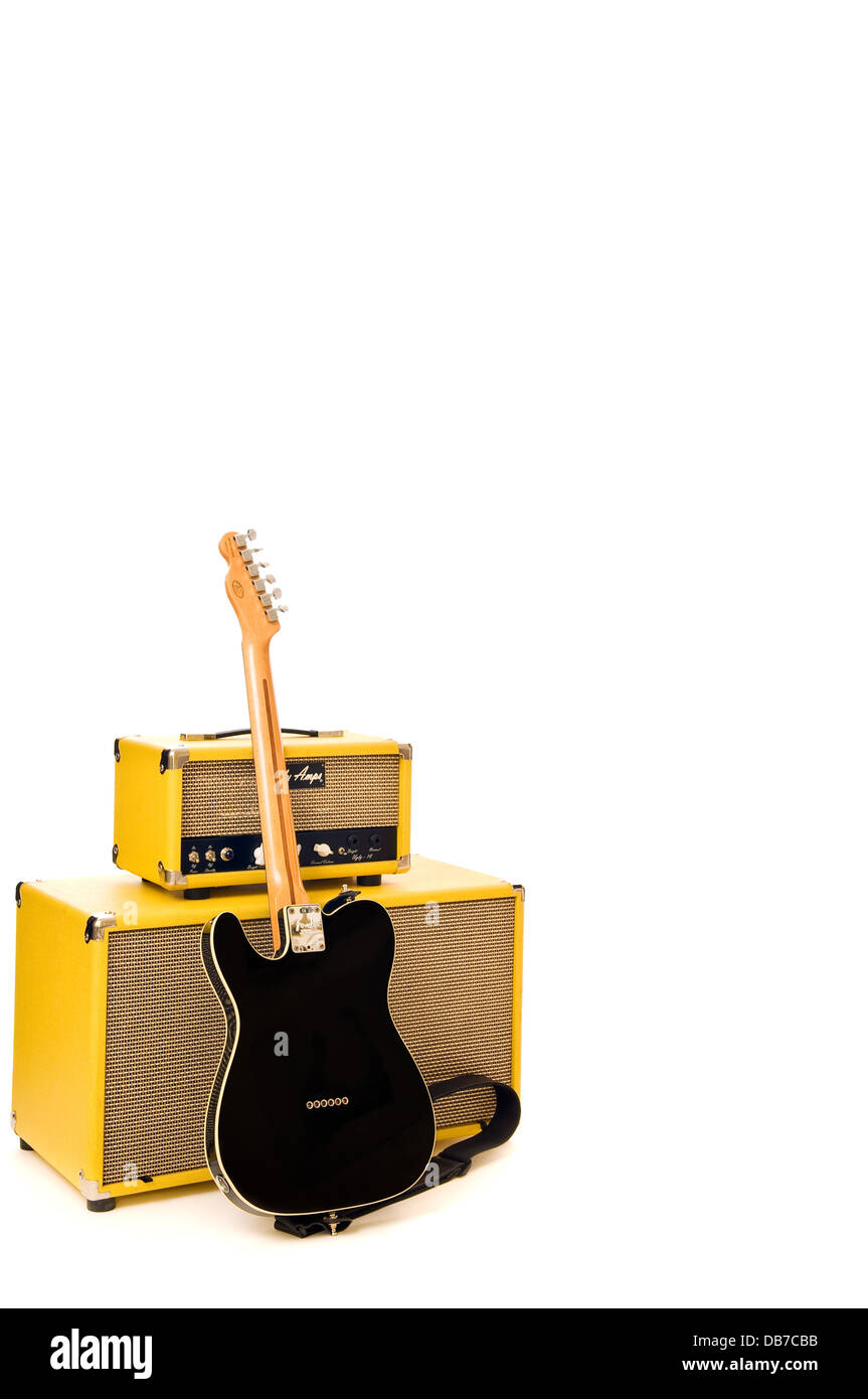 An electric black guitar leaning against 2 stacked yellow amplifiers. Vertical photo with a white background Stock Photo