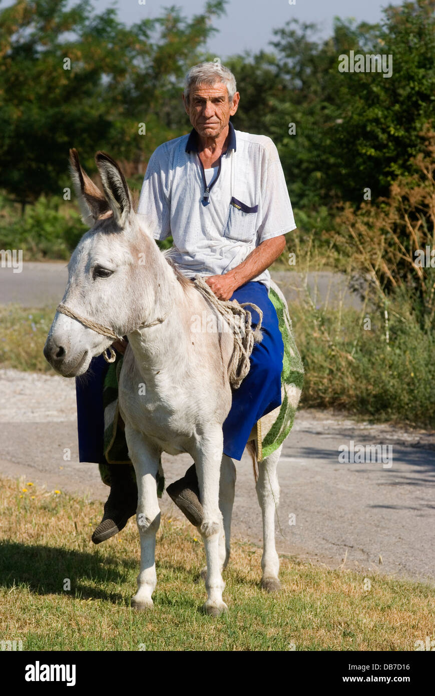 Man rides donkey as his form of transport in rural village Stock Photo