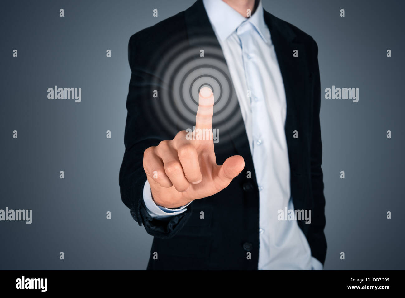 Portrait of business person touching button on invisible screen. Touch screen concept image. Isolated on dark gray background. Stock Photo