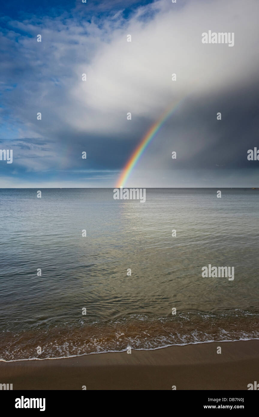 Sandy beach with rainbow over the sea Stock Photo