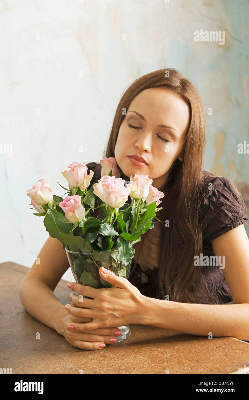 Young woman sitting at a table with flowers in a vase Stock Photo - Alamy