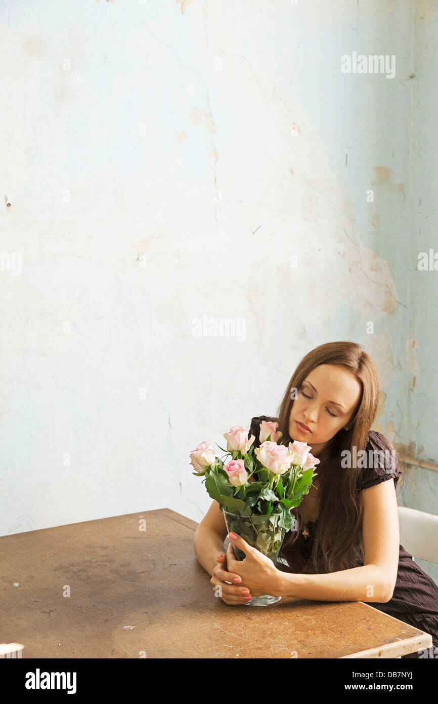 Young woman sitting at a table with flowers in a vase Stock Photo - Alamy