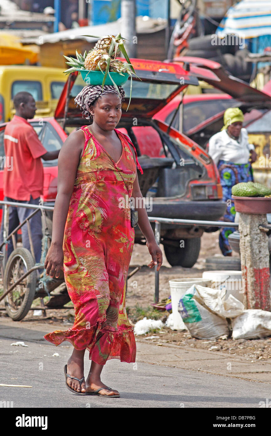 Market woman carrying pineapple on her head Stock Photo