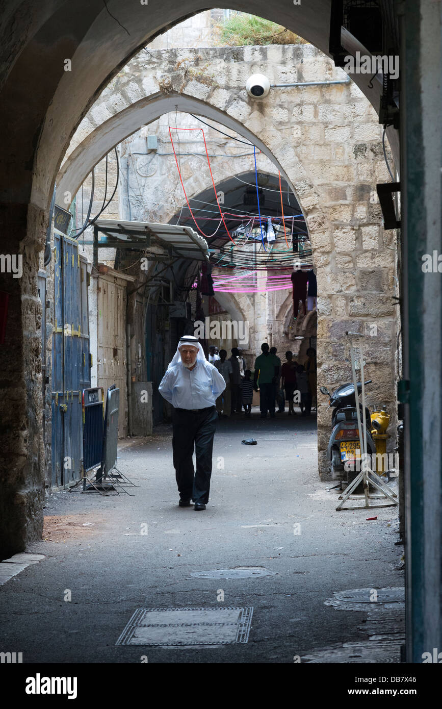 Palestinian man walking under arches. Muslem quarter. Jerusalem Old City. Israel. Stock Photo