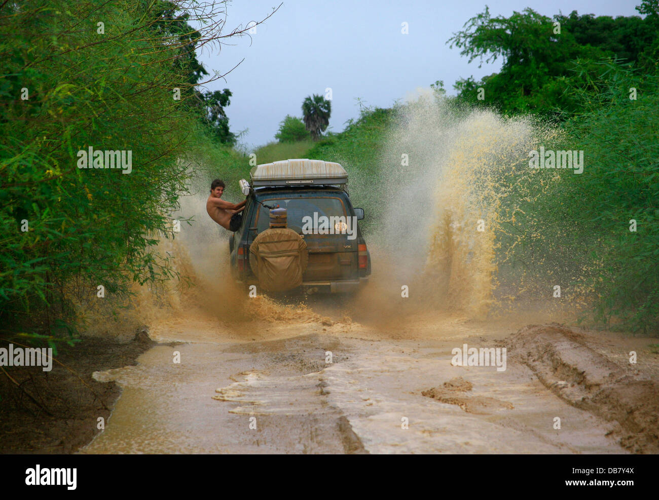 Leisure - 4x4 driving offroad driving adventure 4x4 vehicle drives through mud puddle water man hanging out car dare-devil fun Stock Photo