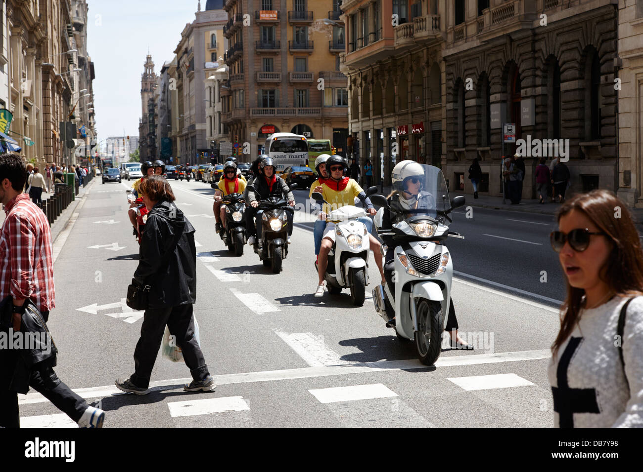 people crossing road in front of waiting scooters on via laietana in the old town of Barcelona Catalonia Spain Stock Photo