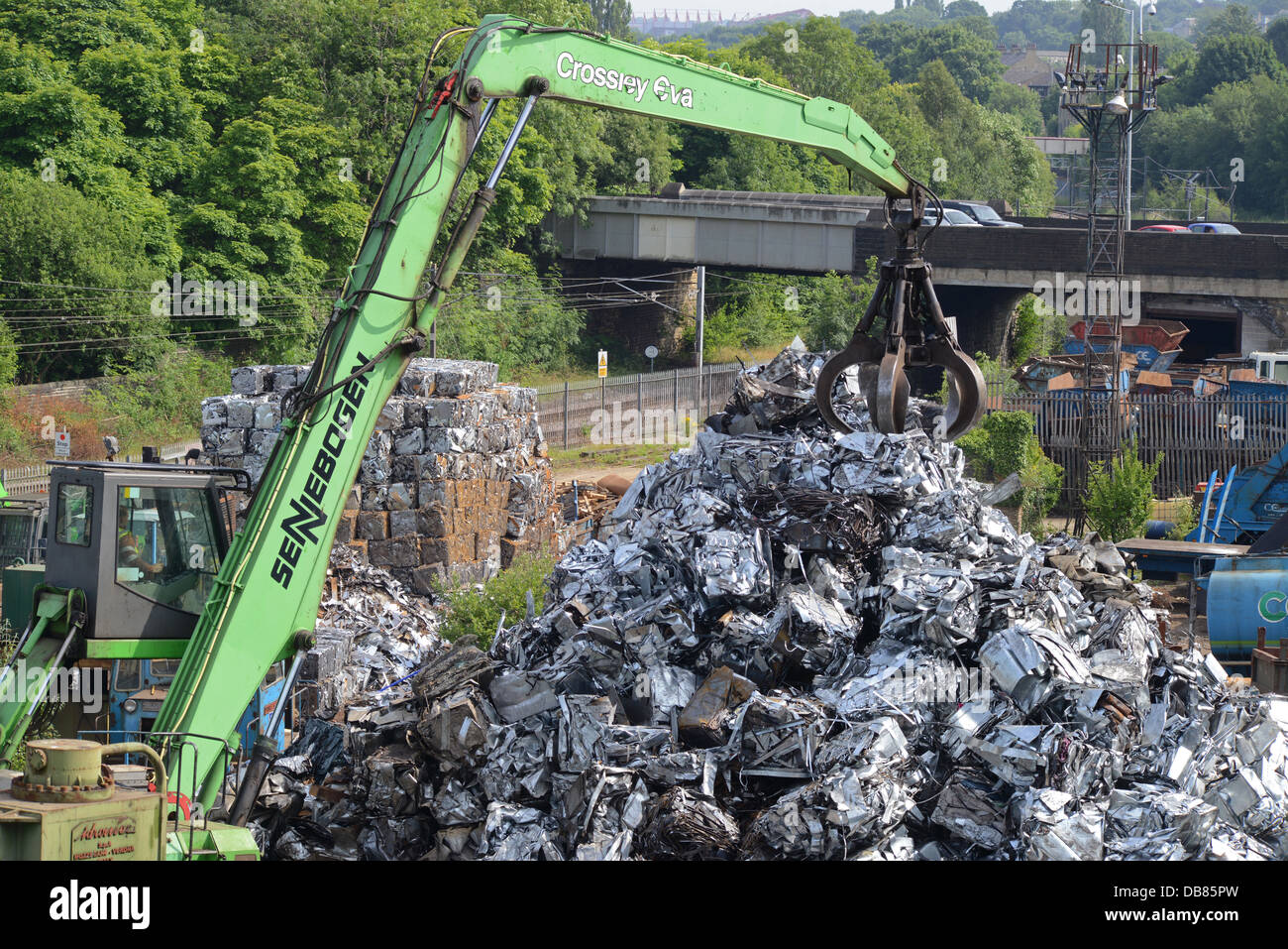 crane driver lifting compacted scrap metal onto pile awaiting transfer to steel works for re-smelting united kingdom Stock Photo