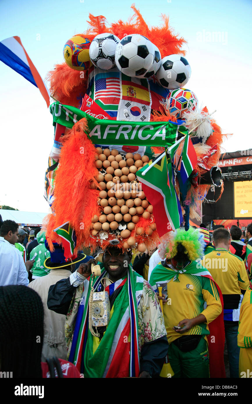 South African fan celebrates Grand Parade fan park pride passion wearing an elaborate headdress holding South African flag in Stock Photo