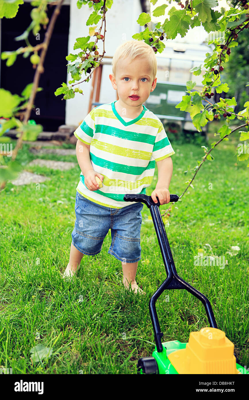 little boy playing with toy tools in the backyard Stock Photo