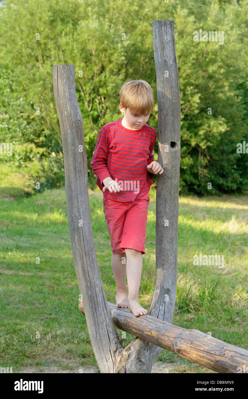 young boy walking along a pole Stock Photo