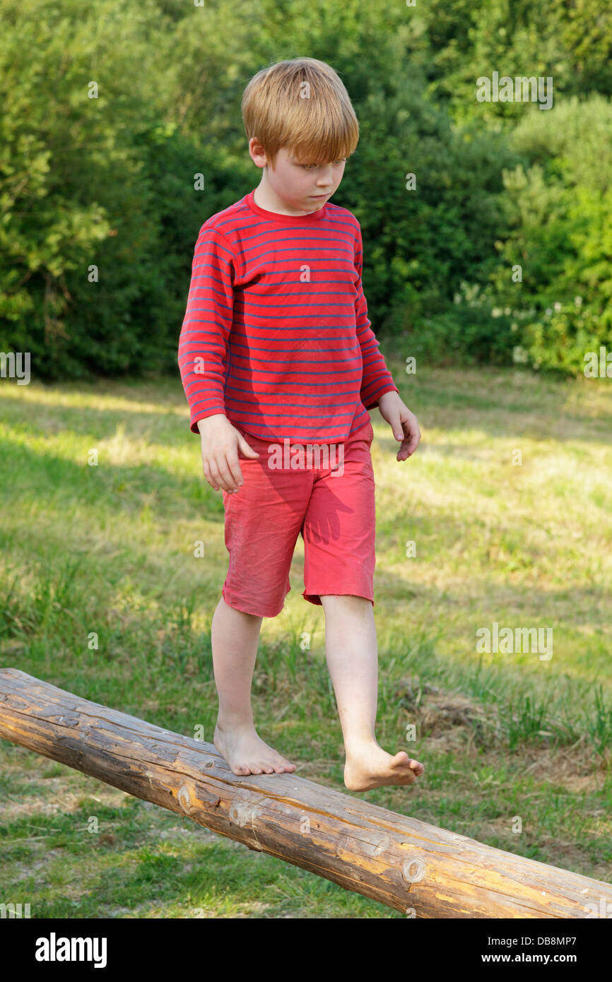young boy walking along a pole Stock Photo