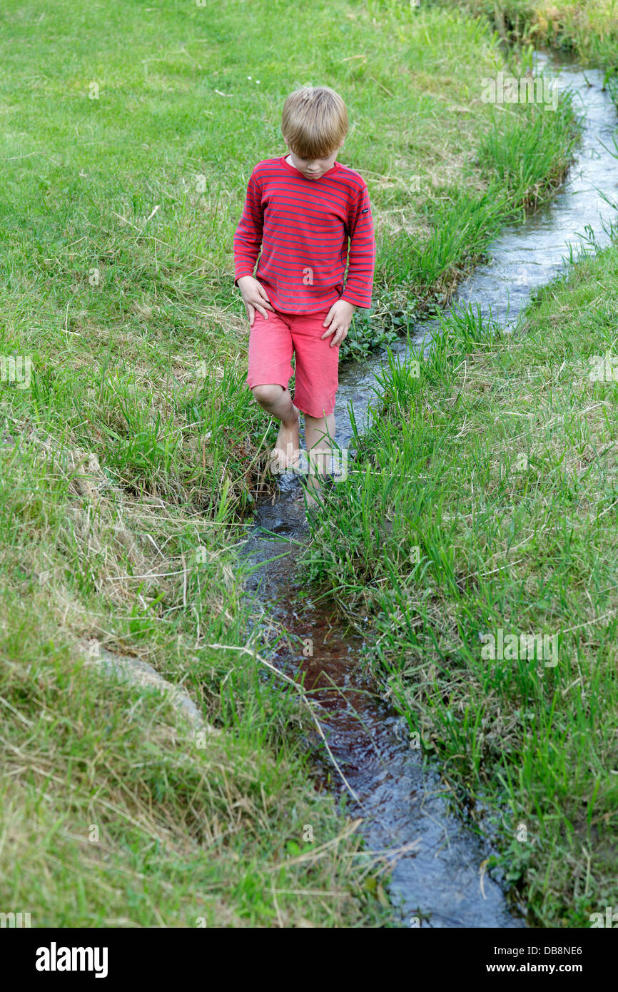 young boy wading through a stream Stock Photo