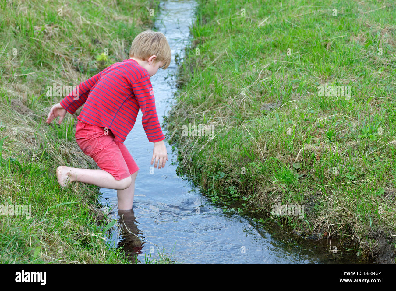 young boy wading through a stream Stock Photo